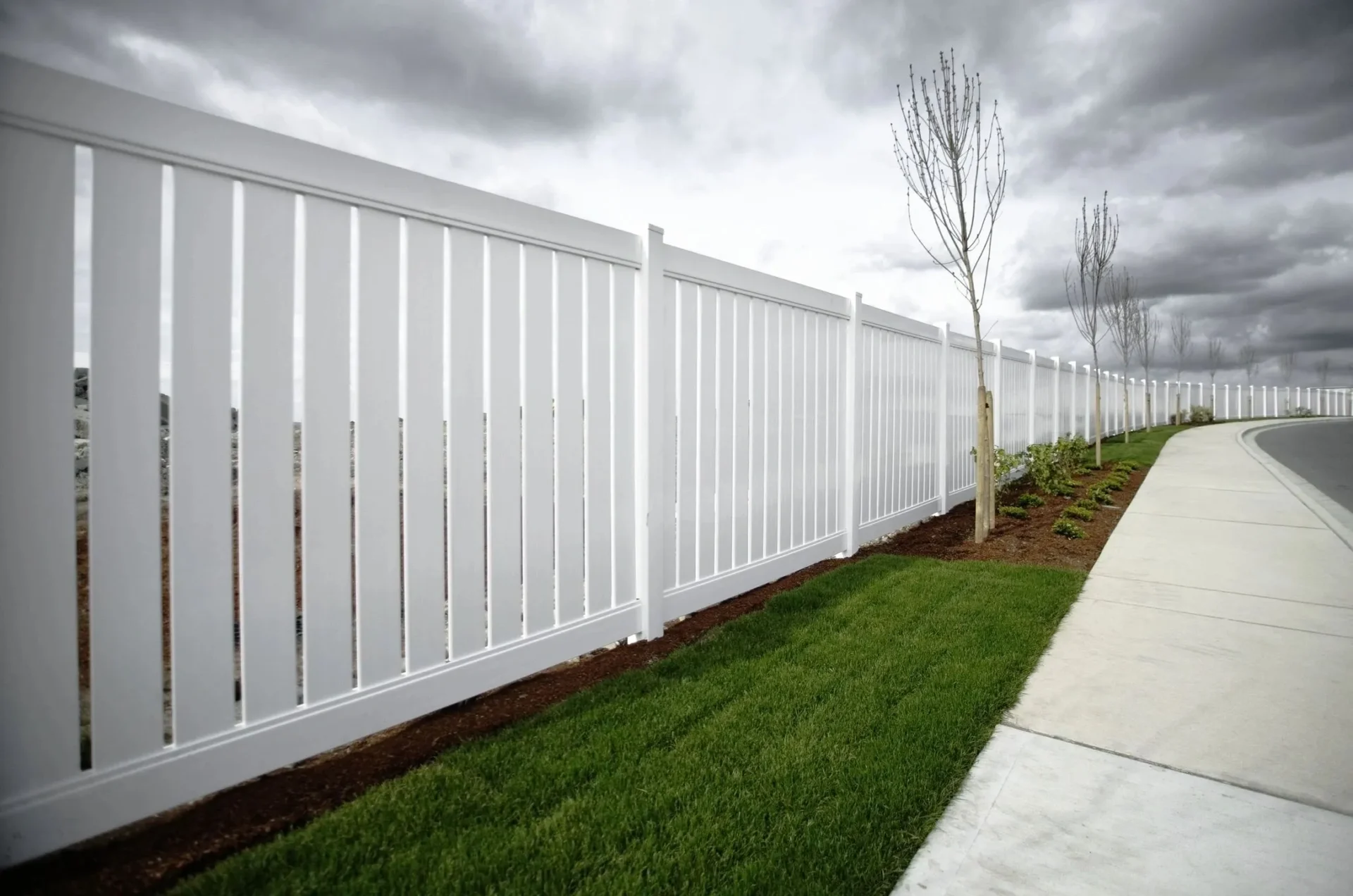 A white fence next to a grassy area.